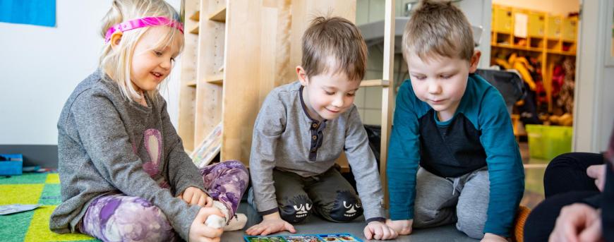 kolme lasta leikkii lattialla